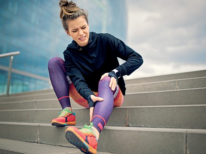Injured runner girl is sitting on the city stairs