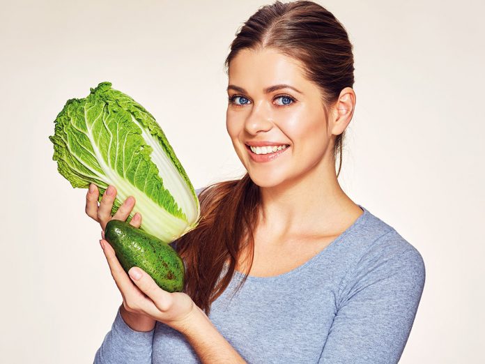 Beautiful young woman studio portrait with cabbage and avocado.