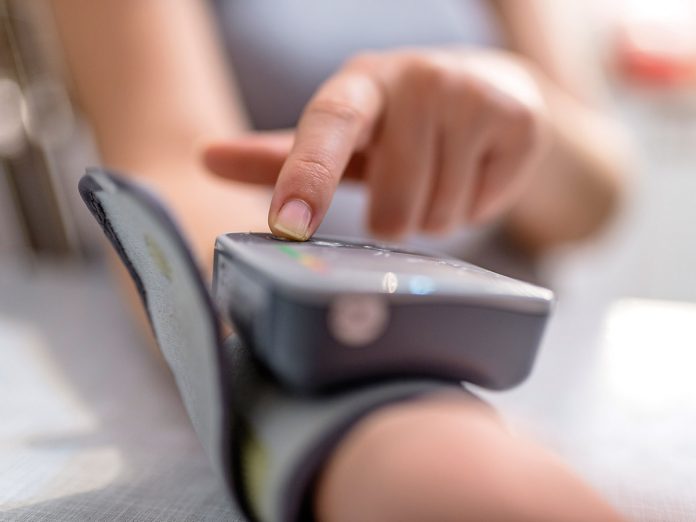 Woman Checking Blood Pressure. Close up view of a blood pressure monito on hand. Digital tonometr on human hand. Portrait of young woman measuring her blood pressure