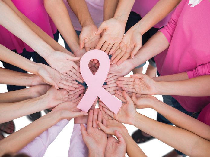 Hands joined in circle holding breast cancer struggle symbol