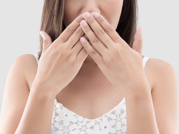 Asian woman use both hands close mouth for not commenting or refusing on gray background